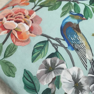 Floral and bird pattern on fabric with an embroidered blue bird and pink flowers.